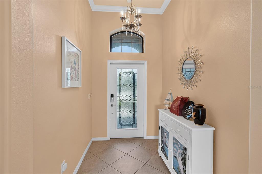 A foyer features a white front door with decorative glass, tile flooring, and a chandelier — 3652 TREASURE COVE CIRCLE, NAPLES, FL