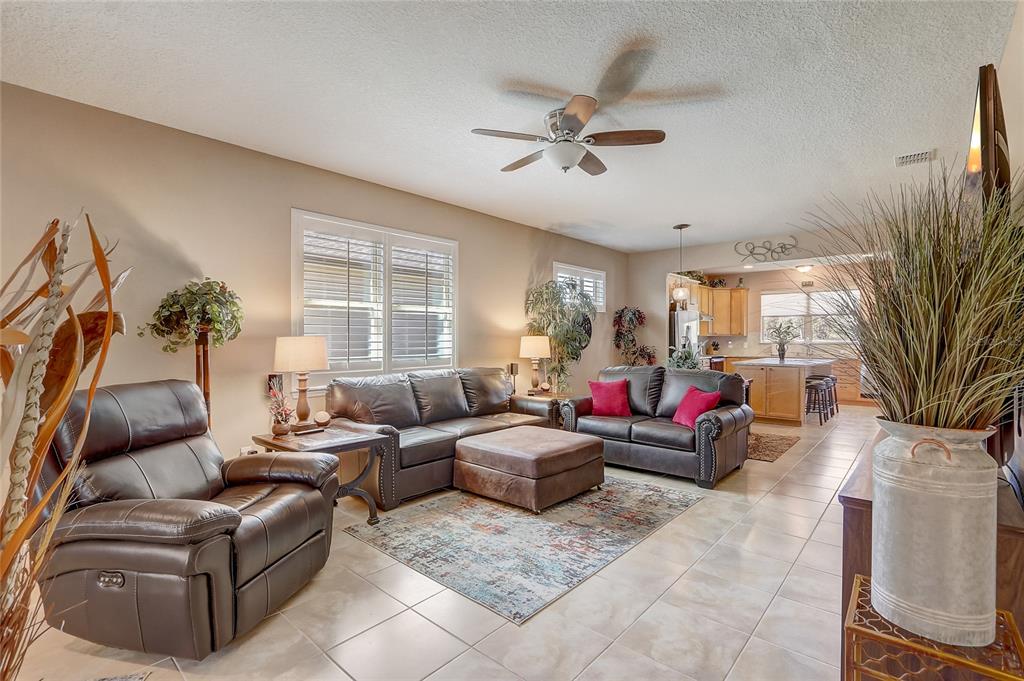 A living room with tile floors, leather furniture, and an open view into the kitchen — 9673 SW 63RD LOOP, OCALA, FL