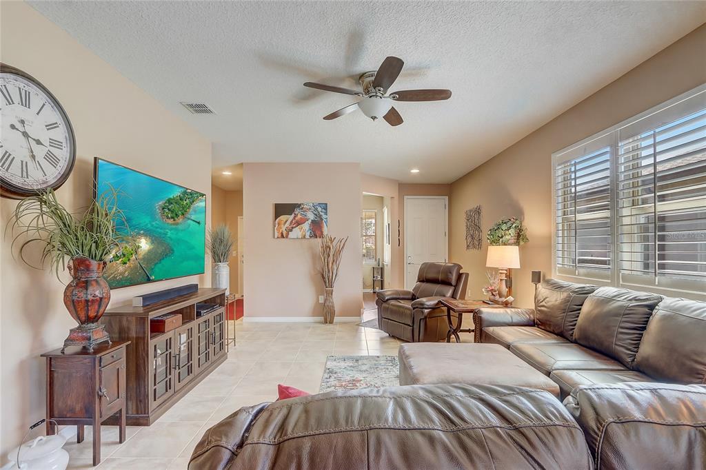 A living room features tile flooring, a leather sectional, a recliner, and a wall-mounted television — 9673 SW 63RD LOOP, OCALA, FL