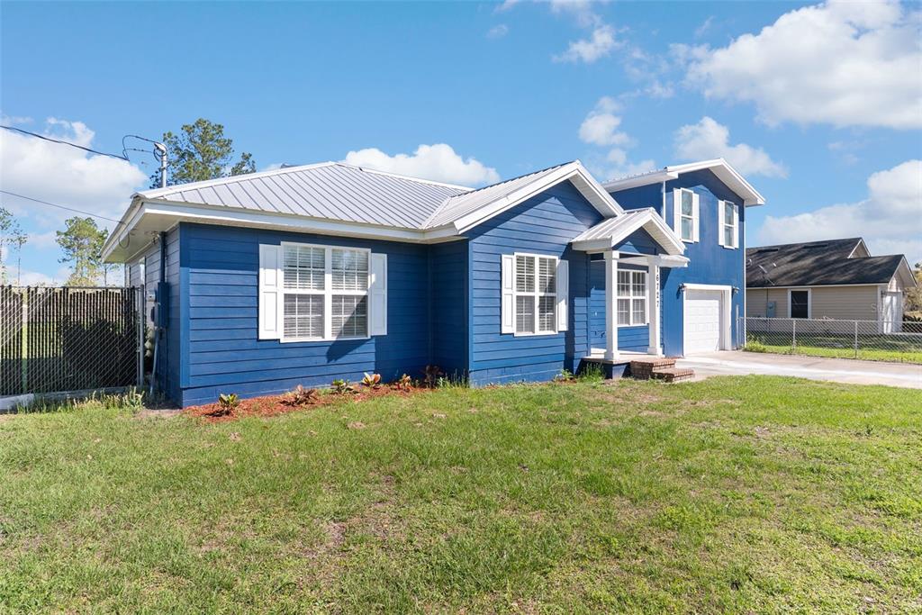 A blue, single-story house with a metal roof and a small attached garage — 16727 SE 91ST STREET, LAKE BUTLER, FL