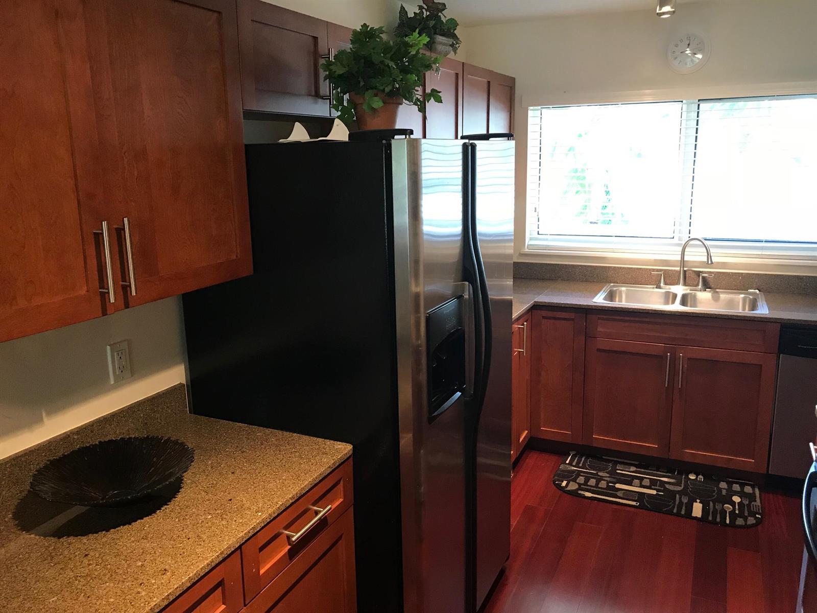 A kitchen features wood cabinets, stainless steel appliances, granite countertops, and a double basin sink — 621 E Woolbright Road # 202, Boynton Beach FL 33435, BOYNTON BEACH, FL