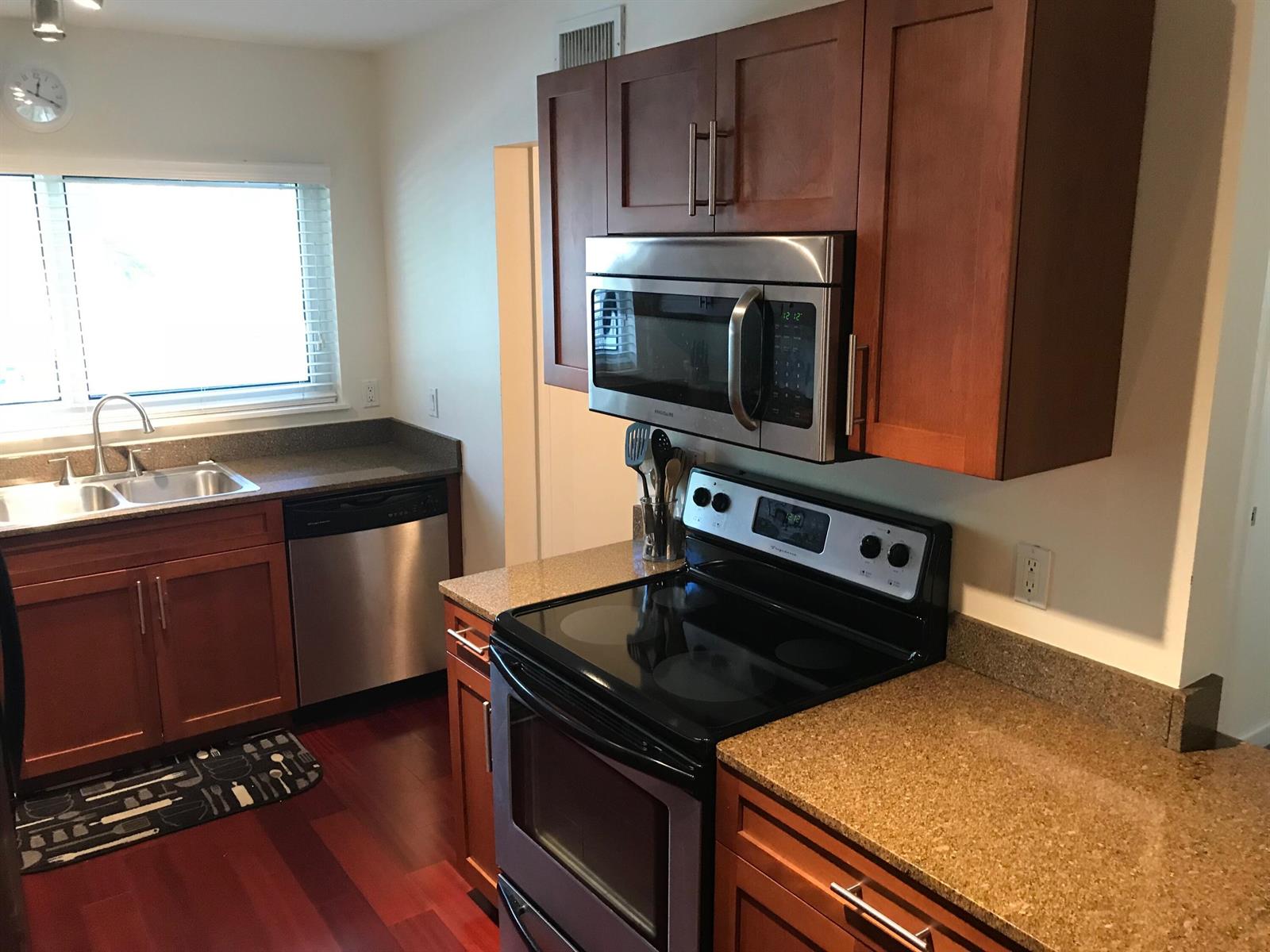 A kitchen features wood cabinets, stainless steel appliances, and speckled granite countertops — 621 E Woolbright Road # 202, Boynton Beach FL 33435, BOYNTON BEACH, FL