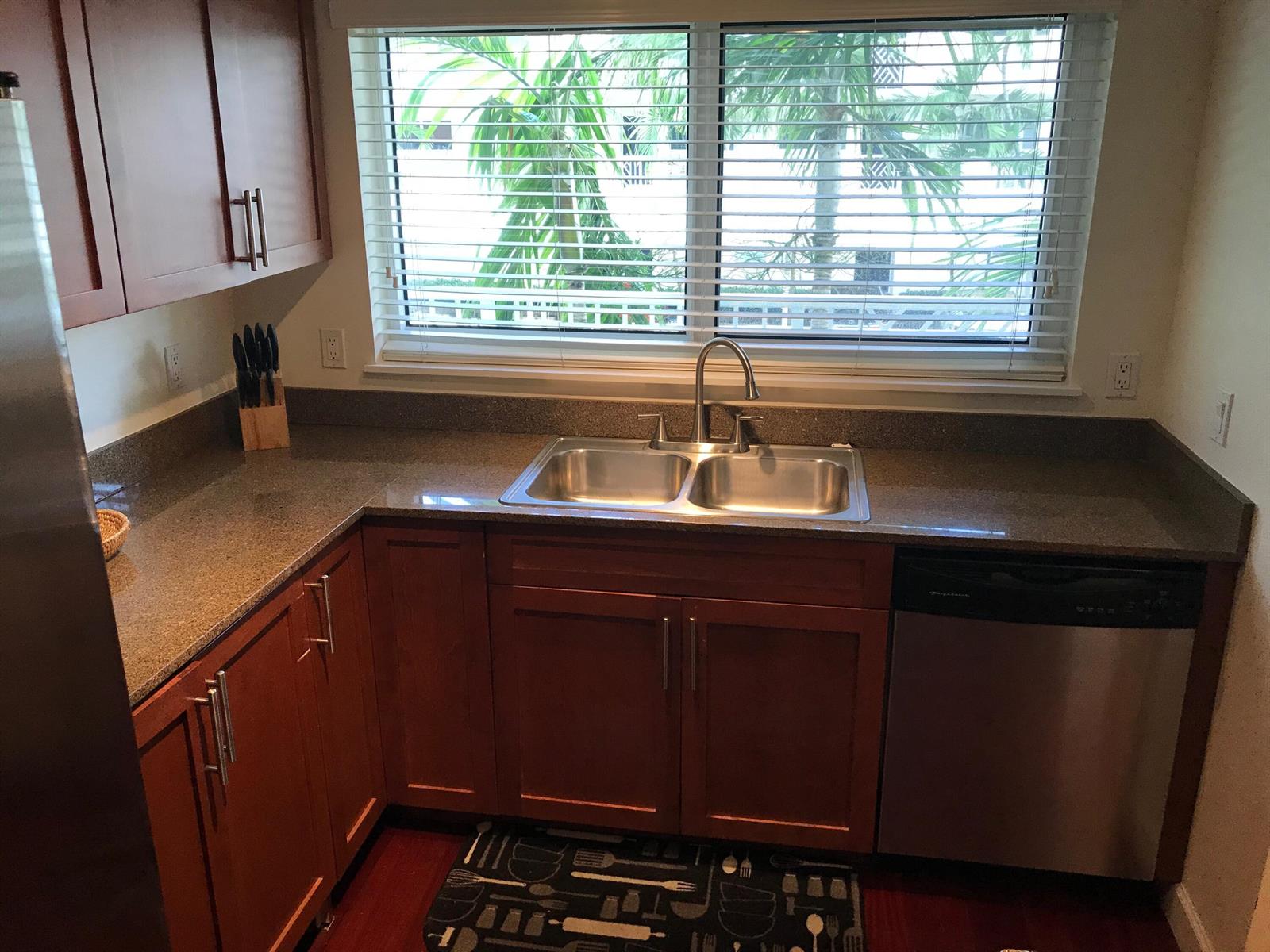 A kitchen features wood cabinets, granite countertops, a double-basin sink, and a window with blinds — 621 E Woolbright Road # 202, Boynton Beach FL 33435, BOYNTON BEACH, FL