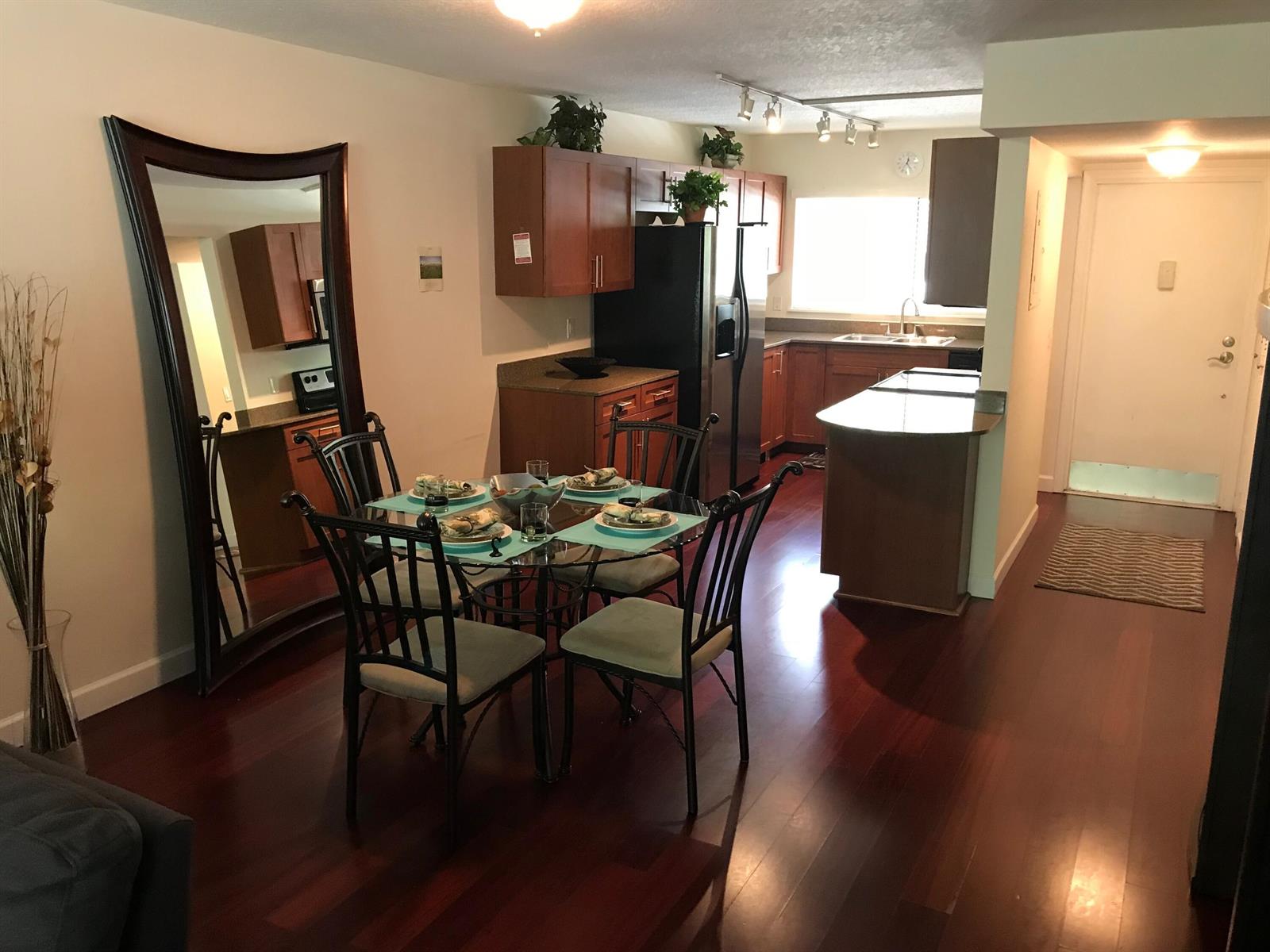 A dining area with a glass table and chairs sits adjacent to a wood-cabinet kitchen — 621 E Woolbright Road # 202, Boynton Beach FL 33435, BOYNTON BEACH, FL