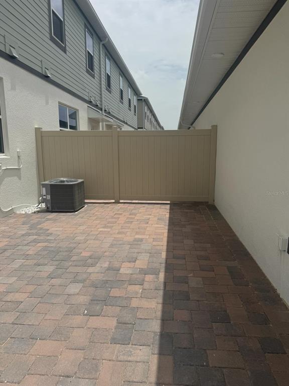 A paved patio area is enclosed by a tan privacy fence between two residential buildings — 564 POTHOS STREET, APOPKA, FL