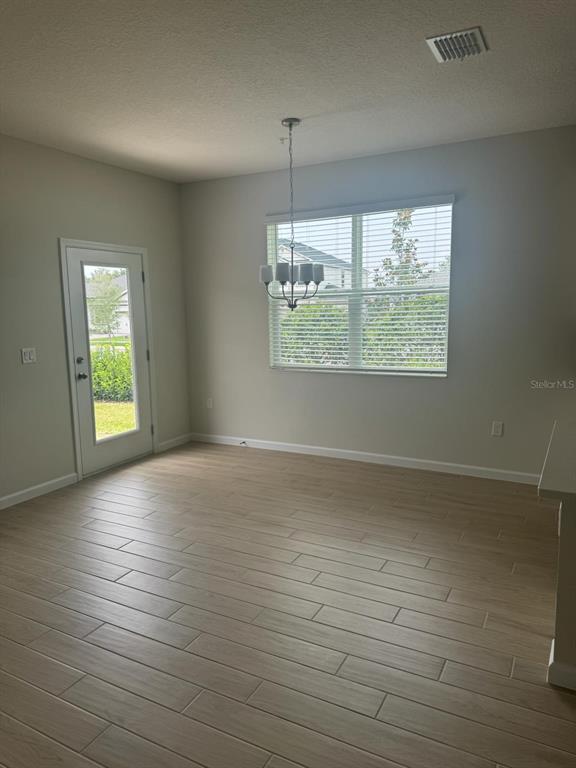 A dining area with light wood-look tile flooring, a chandelier, and a glass-paneled exterior door — 564 POTHOS STREET, APOPKA, FL