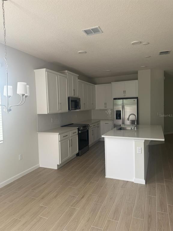 A kitchen with white cabinets, stainless steel appliances, and a central island with a sink — 564 POTHOS STREET, APOPKA, FL