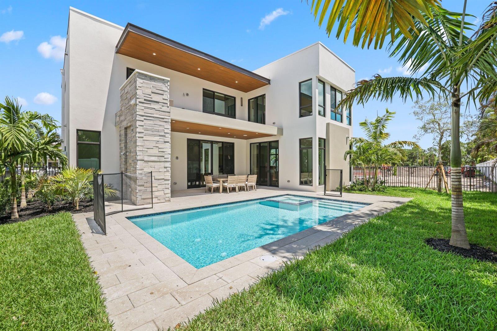A modern two-story house features a stone accent wall, a swimming pool, and patio seating — 16702 Mosaic Place, Delray Beach FL 33446, DELRAY BEACH, FL