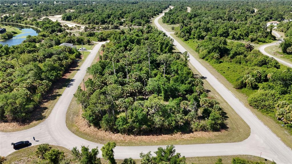 An aerial view shows a wooded, undeveloped residential lot surrounded by paved roads — 2515 COLONY CIRCLE, NORTH PORT, FL