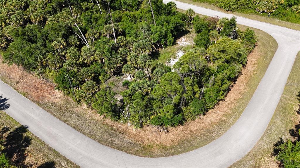 An aerial view shows a wooded, undeveloped corner lot bordered by two paved roads — 2515 COLONY CIRCLE, NORTH PORT, FL