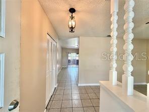 A tiled entryway leads to a living area featuring decorative white columns and a chandelier — 1507 N THACKER AVENUE, KISSIMMEE, FL