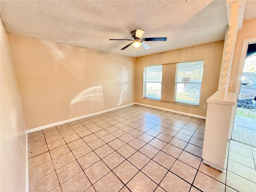 An empty room with beige walls, tile flooring, a ceiling fan, and two windows — 1507 N THACKER AVENUE, KISSIMMEE, FL