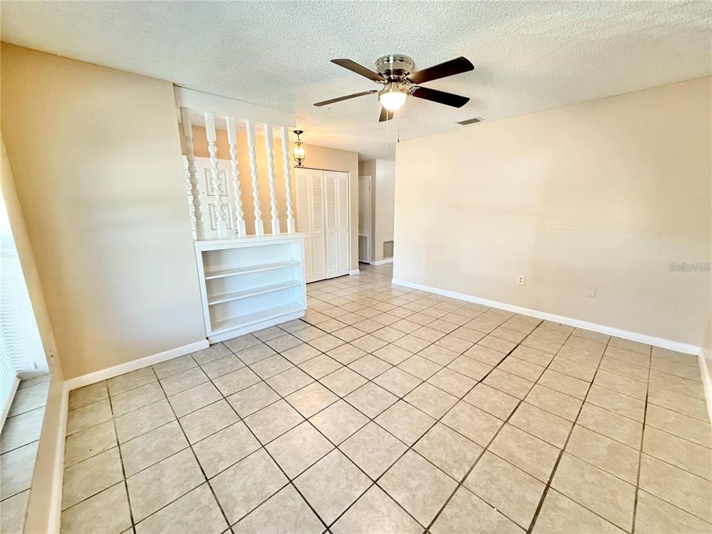 A room with beige walls, tiled floors, a ceiling fan, and a white room divider — 1507 N THACKER AVENUE, KISSIMMEE, FL