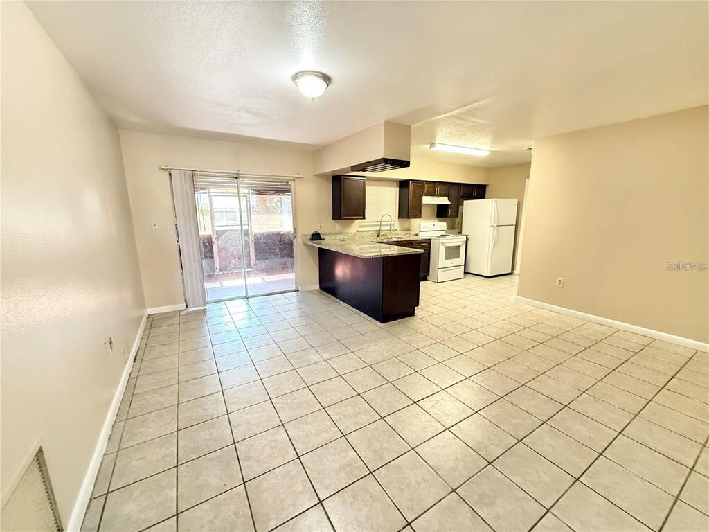 An open-concept kitchen and dining area features tile flooring, dark cabinetry, and sliding glass doors — 1507 N THACKER AVENUE, KISSIMMEE, FL