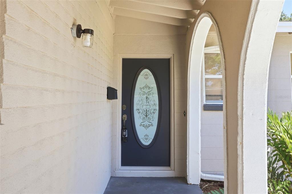 A dark front door with an oval glass insert sits under a covered entryway — 511 OXFORD COURT, ORLANDO, FL