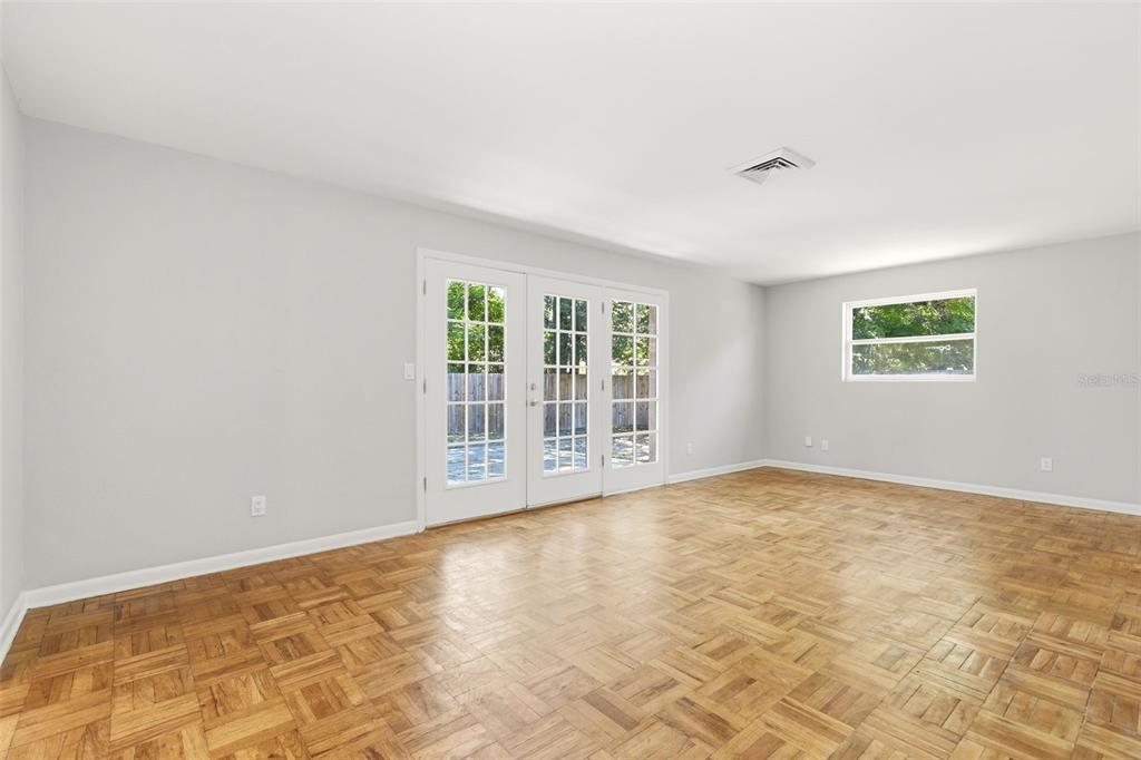 An empty room features light gray walls, parquet wood flooring, French doors, and a window — 511 OXFORD COURT, ORLANDO, FL