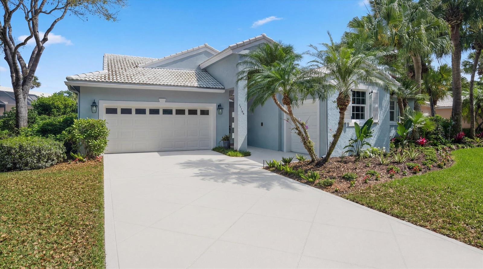 A light blue single-story house features a two-car garage, a tiled roof, and palm trees — 17104 Crossgate Drive, Jupiter FL 33477, JUPITER, FL