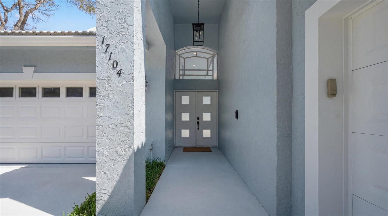 A light blue house exterior features a double front door with square glass panels — 17104 Crossgate Drive, Jupiter FL 33477, JUPITER, FL