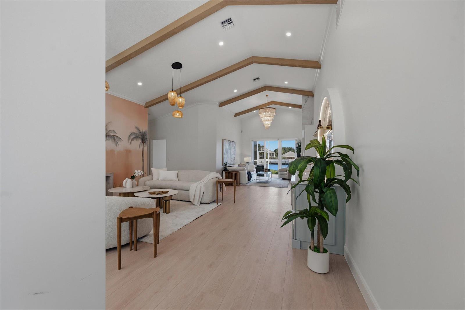 A bright, open-concept living room features vaulted ceilings with exposed wooden beams and water views — 17104 Crossgate Drive, Jupiter FL 33477, JUPITER, FL