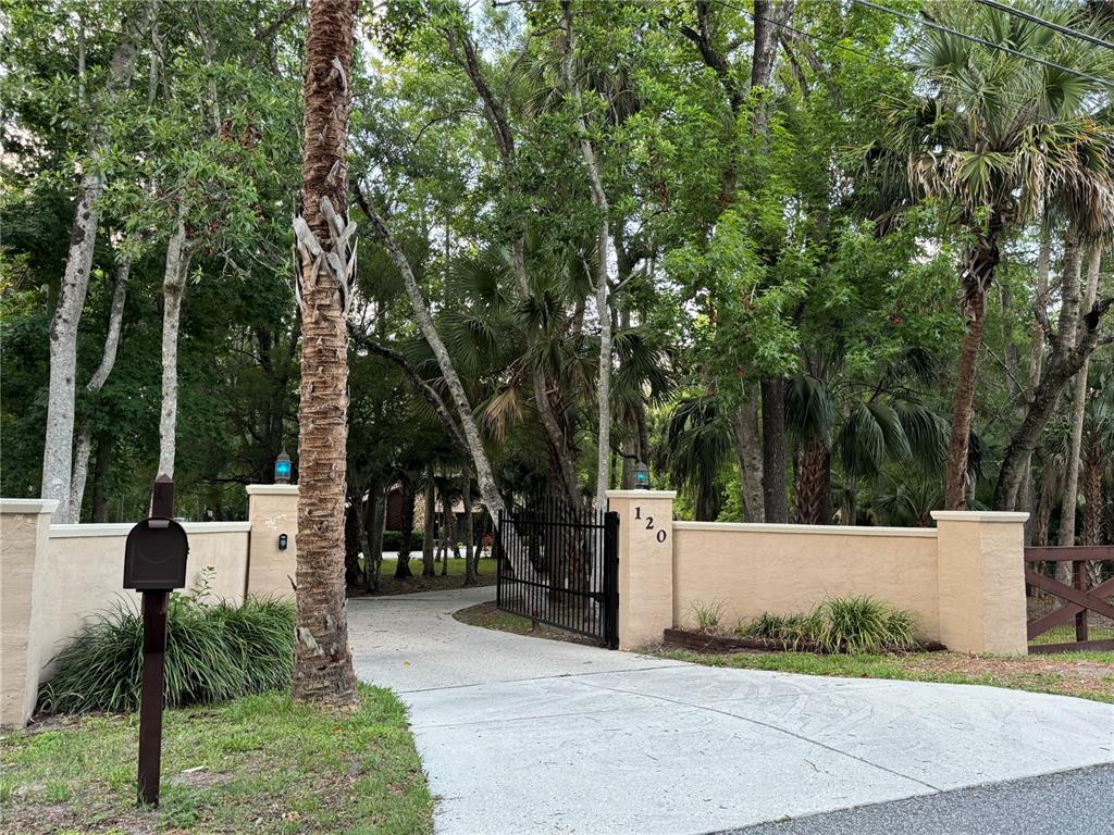 A spacious living room features a tall stone fireplace, hardwood floors, and a vaulted ceiling — 120 E BAHAMA ROAD, WINTER SPRINGS, FL