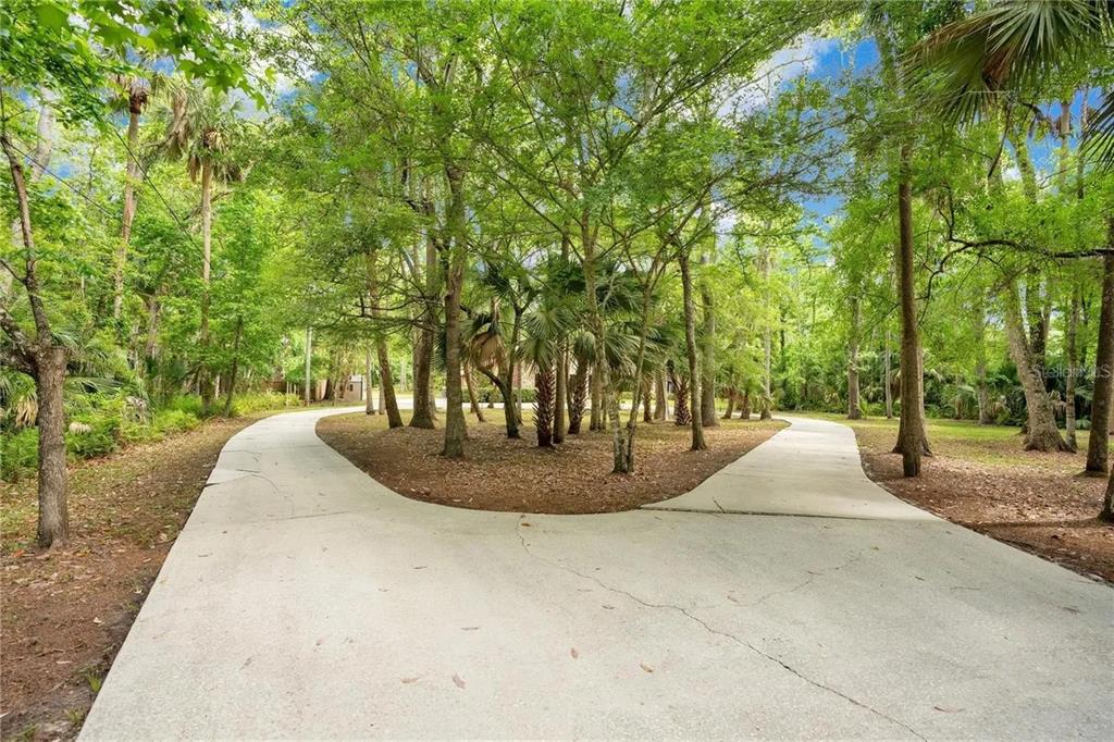A living room features a stone fireplace, wood flooring, and a wooden staircase — 120 E BAHAMA ROAD, WINTER SPRINGS, FL