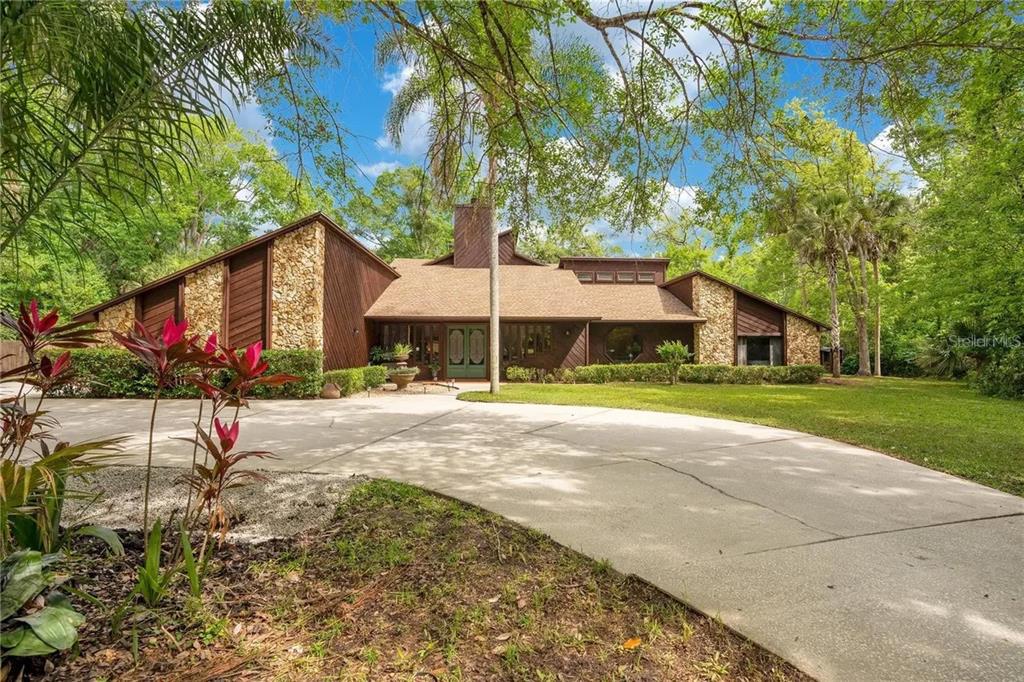 A spacious living room features wood flooring, a stone fireplace, and a staircase with railings — 120 E BAHAMA ROAD, WINTER SPRINGS, FL