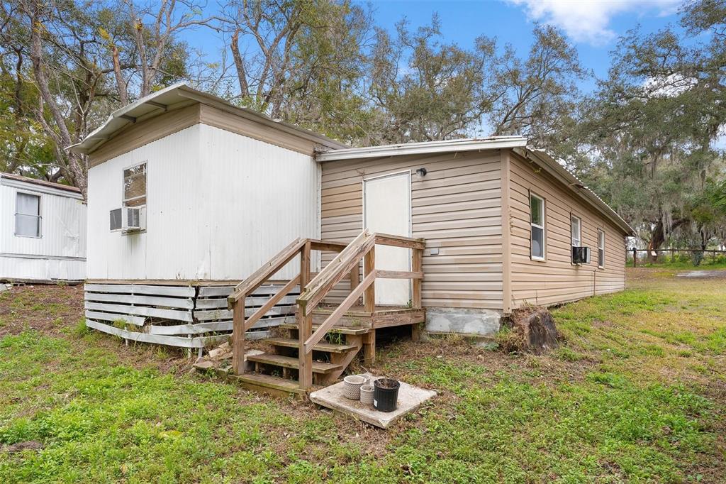 A mobile home with white and tan siding, wooden stairs, and a grassy yard — 2107 HIALEAH AVENUE, LEESBURG, FL