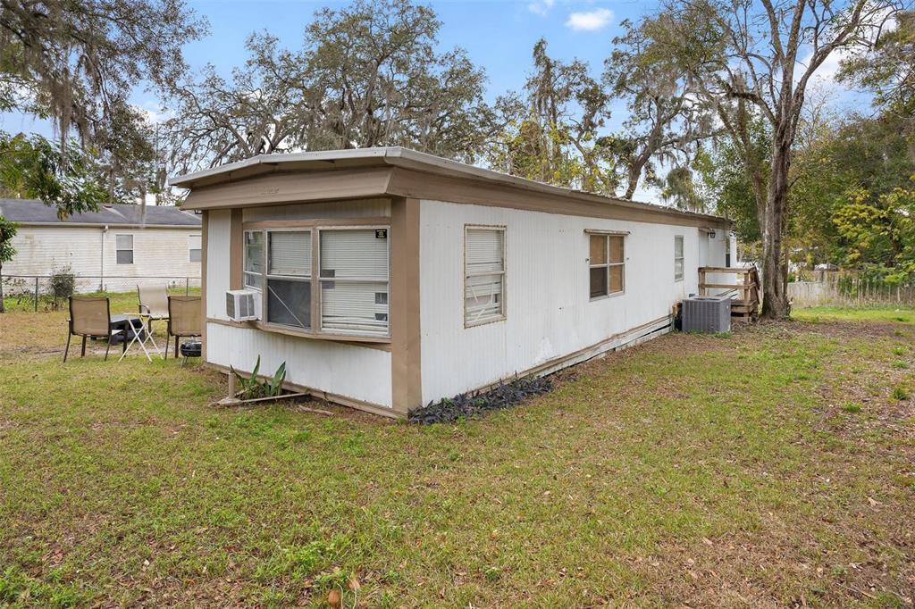 A single-wide mobile home with white siding and a brown roof sits on a grassy lot — 2107 HIALEAH AVENUE, LEESBURG, FL