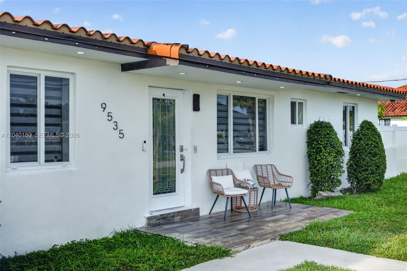 The exterior of a white house features a tiled roof, a front porch, and two chairs — 9535 SW 42nd St, Miami FL 33165, MIAMI, FL