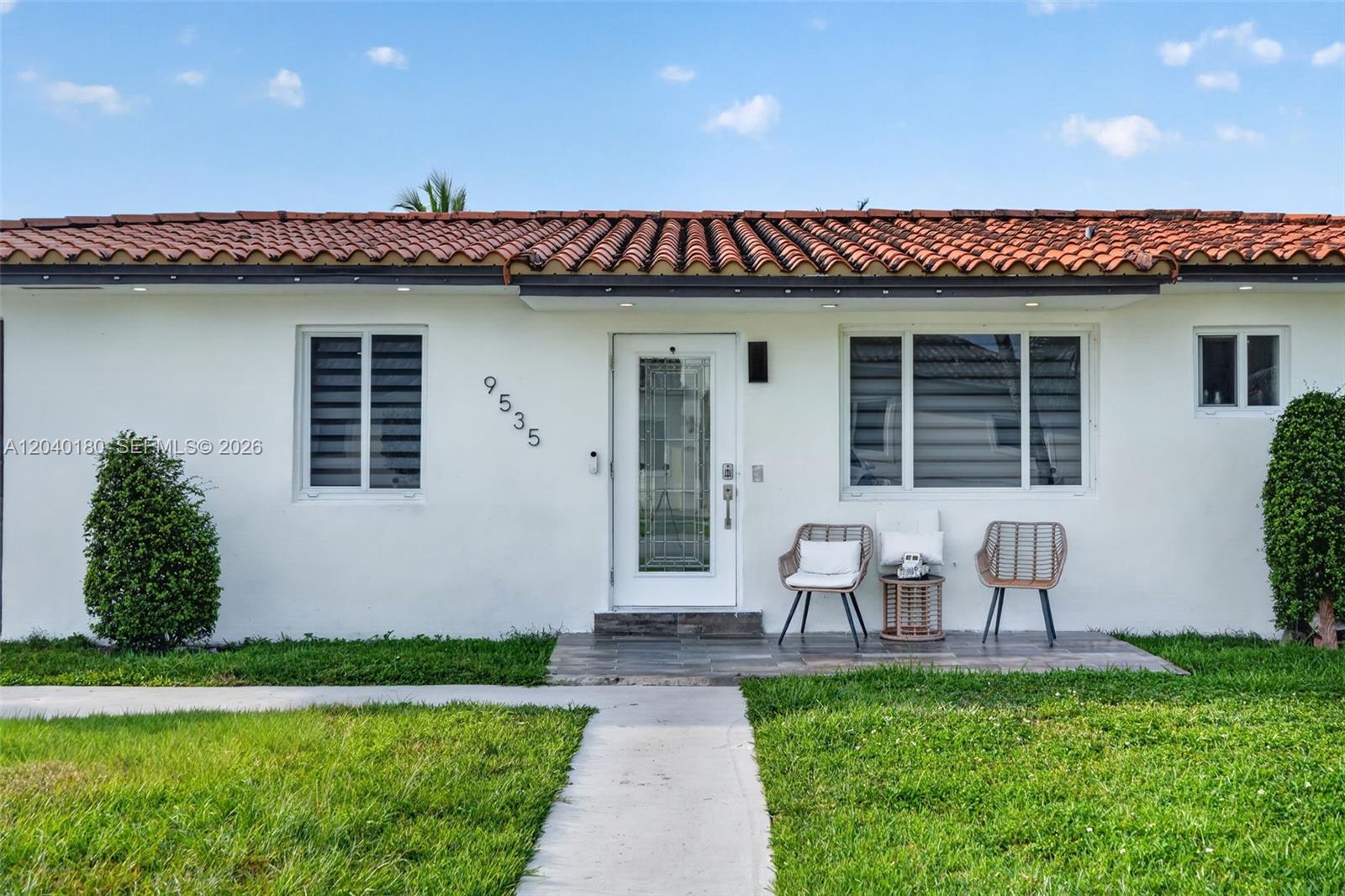A white house exterior features a tiled roof, a front door, and two patio chairs — 9535 SW 42nd St, Miami FL 33165, MIAMI, FL