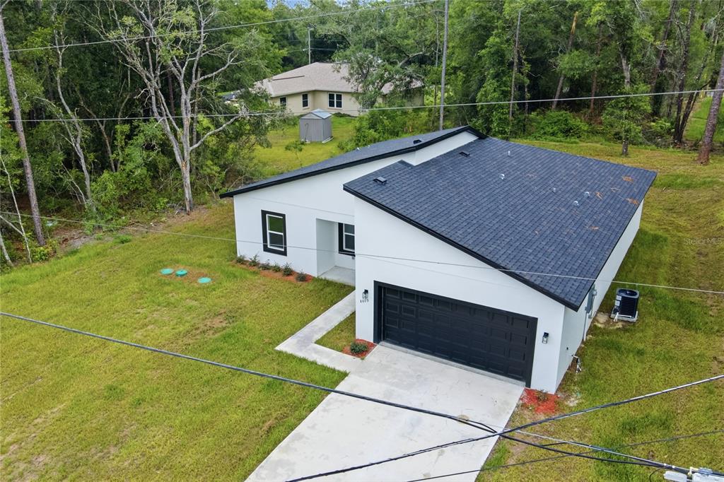 An aerial view of a modern white house with a black roof and garage — 8809 N CIRCULAR WAY, CITRUS SPRINGS, FL