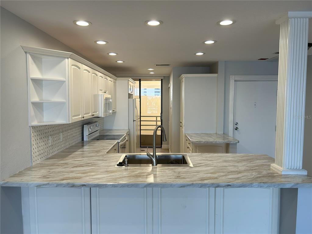 A kitchen features white cabinets, marble-patterned countertops, a stainless steel sink, and recessed lighting — 2775 KIPPS COLONY DRIVE S UNIT 304, ST PETERSBURG, FL