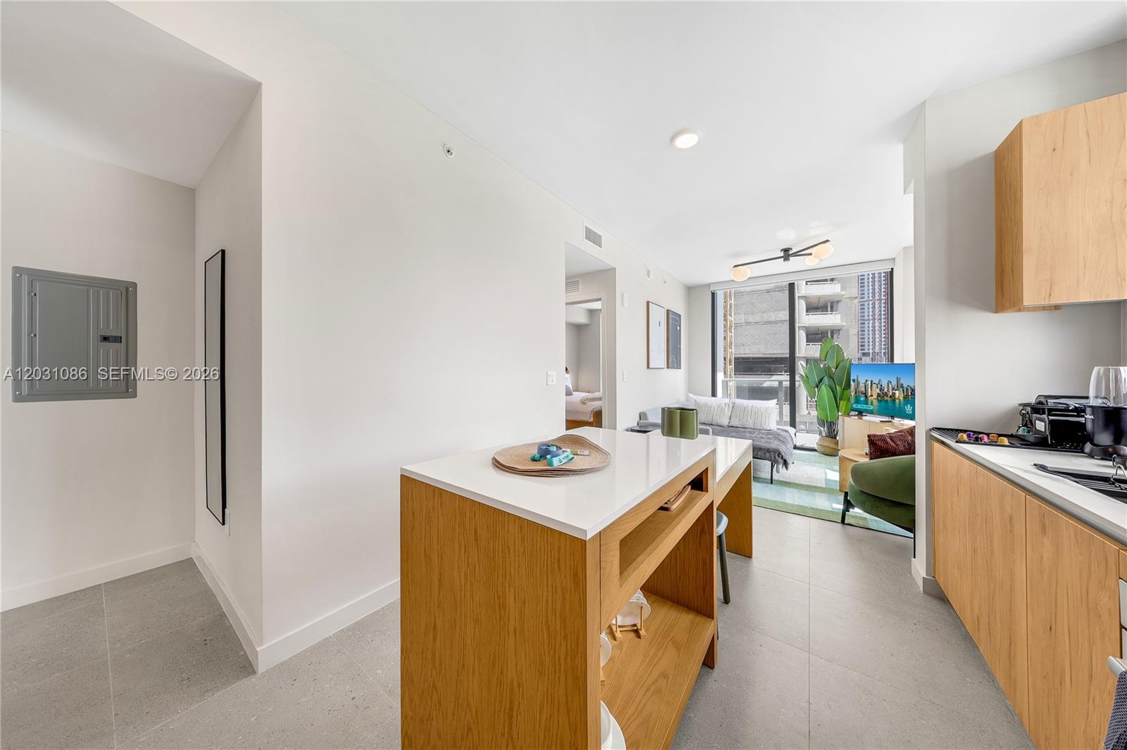 A modern kitchen with light wood cabinetry and a central island overlooks a living area — 11 NE 6th St # 301, Miami FL 33132, MIAMI, FL
