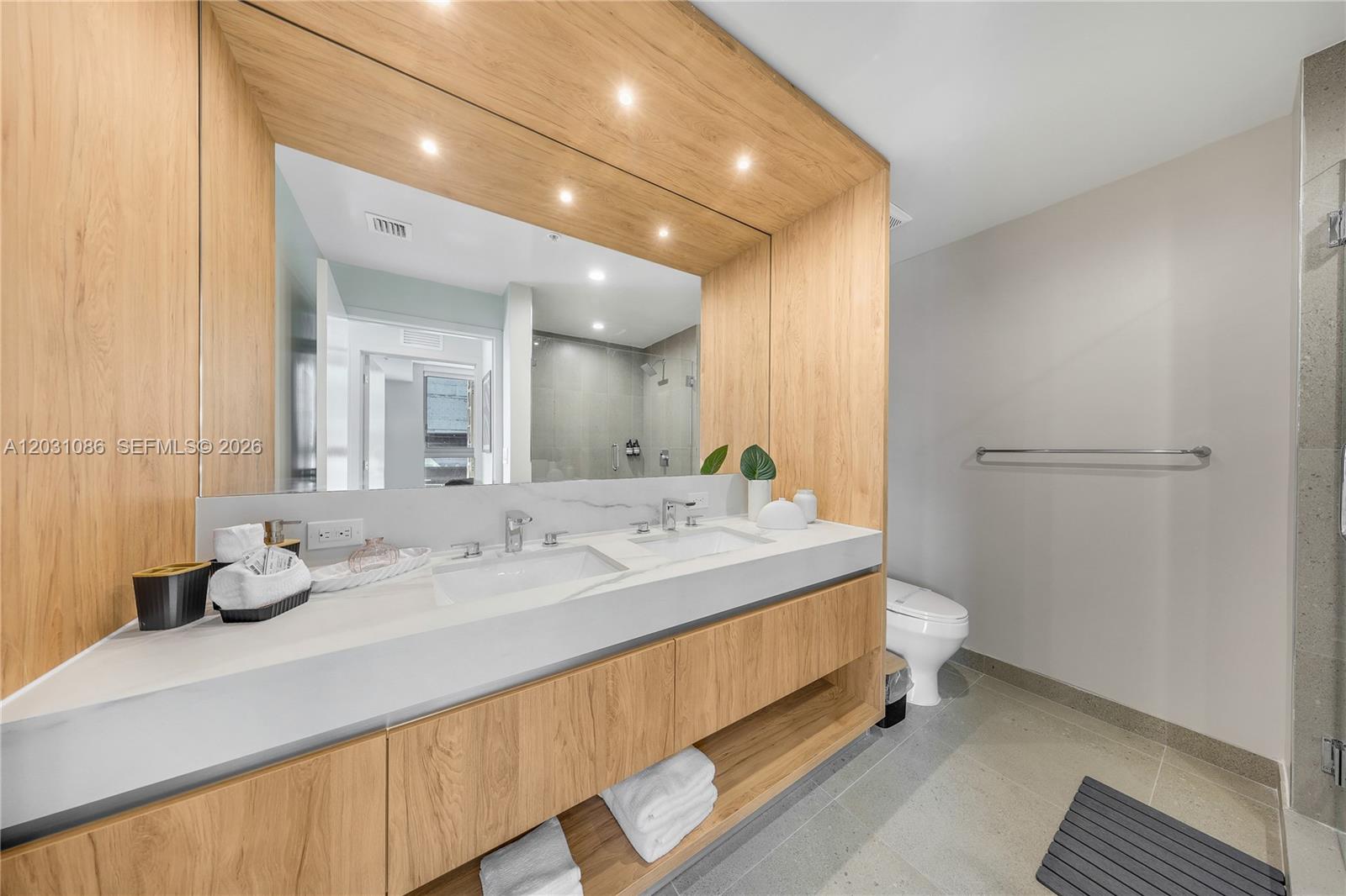 A modern bathroom features a double vanity with light wood cabinetry and a white countertop — 11 NE 6th St # 301, Miami FL 33132, MIAMI, FL