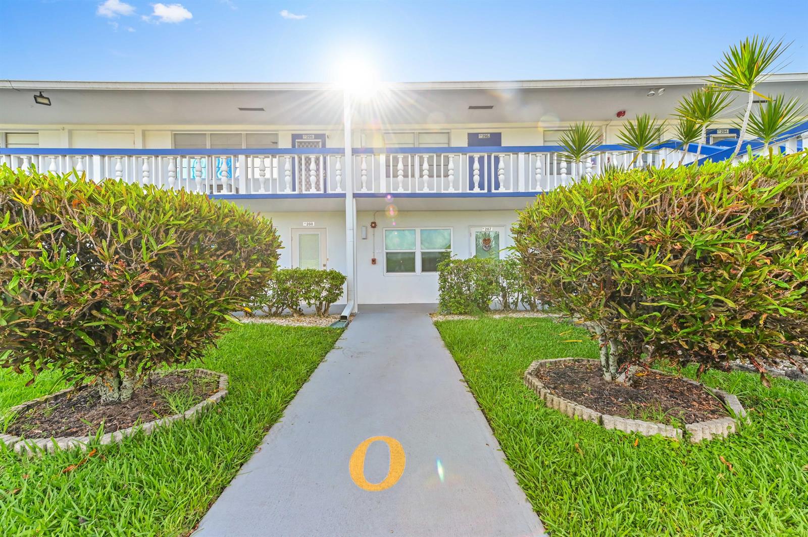 A two-story apartment building exterior features a concrete walkway leading to ground-floor unit entrances — 294 Prescott O, Deerfield Beach FL 33442, DEERFIELD BEACH, FL