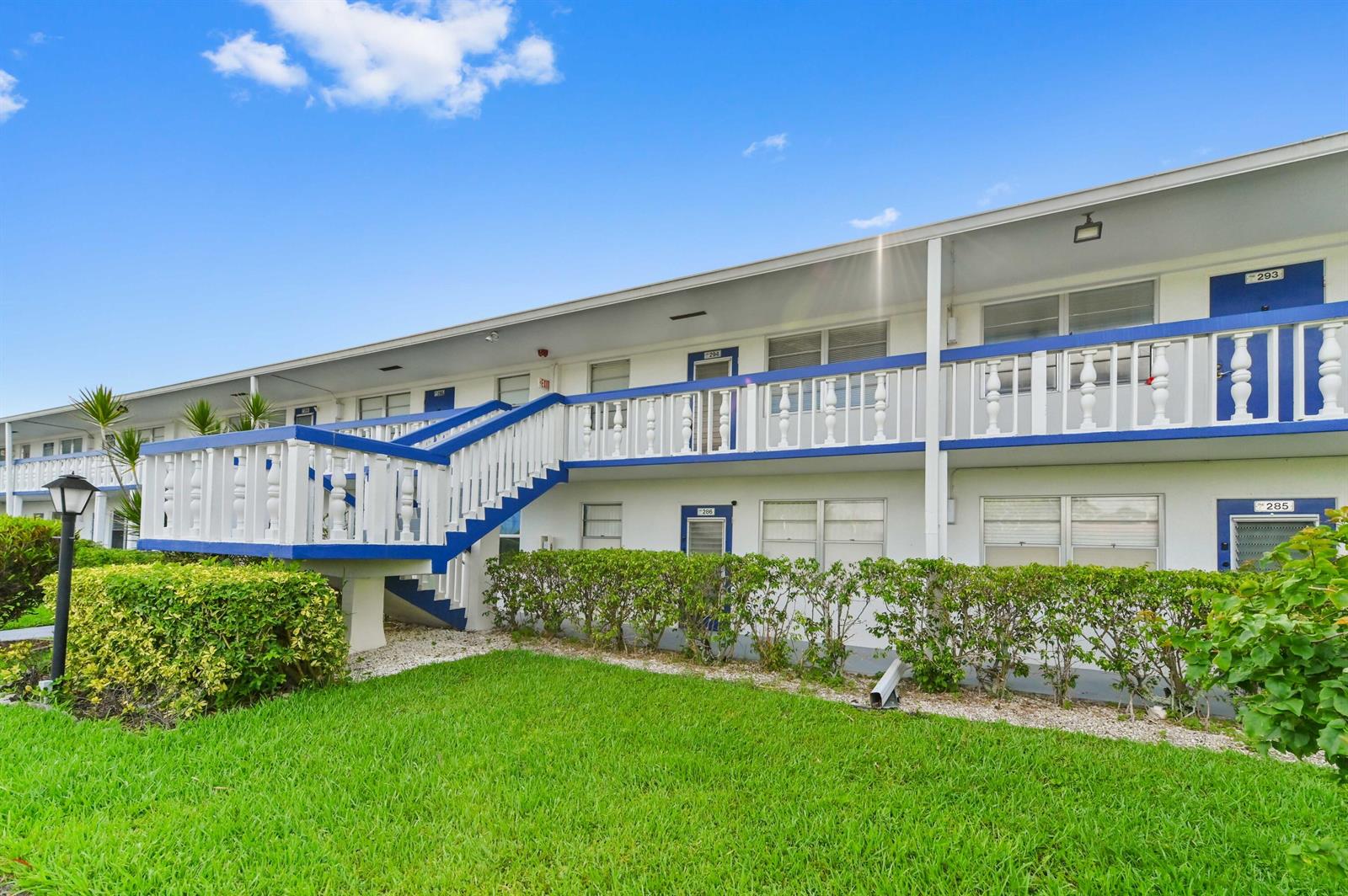 A two-story apartment building features white walls, blue trim, and an exterior staircase — 294 Prescott O, Deerfield Beach FL 33442, DEERFIELD BEACH, FL