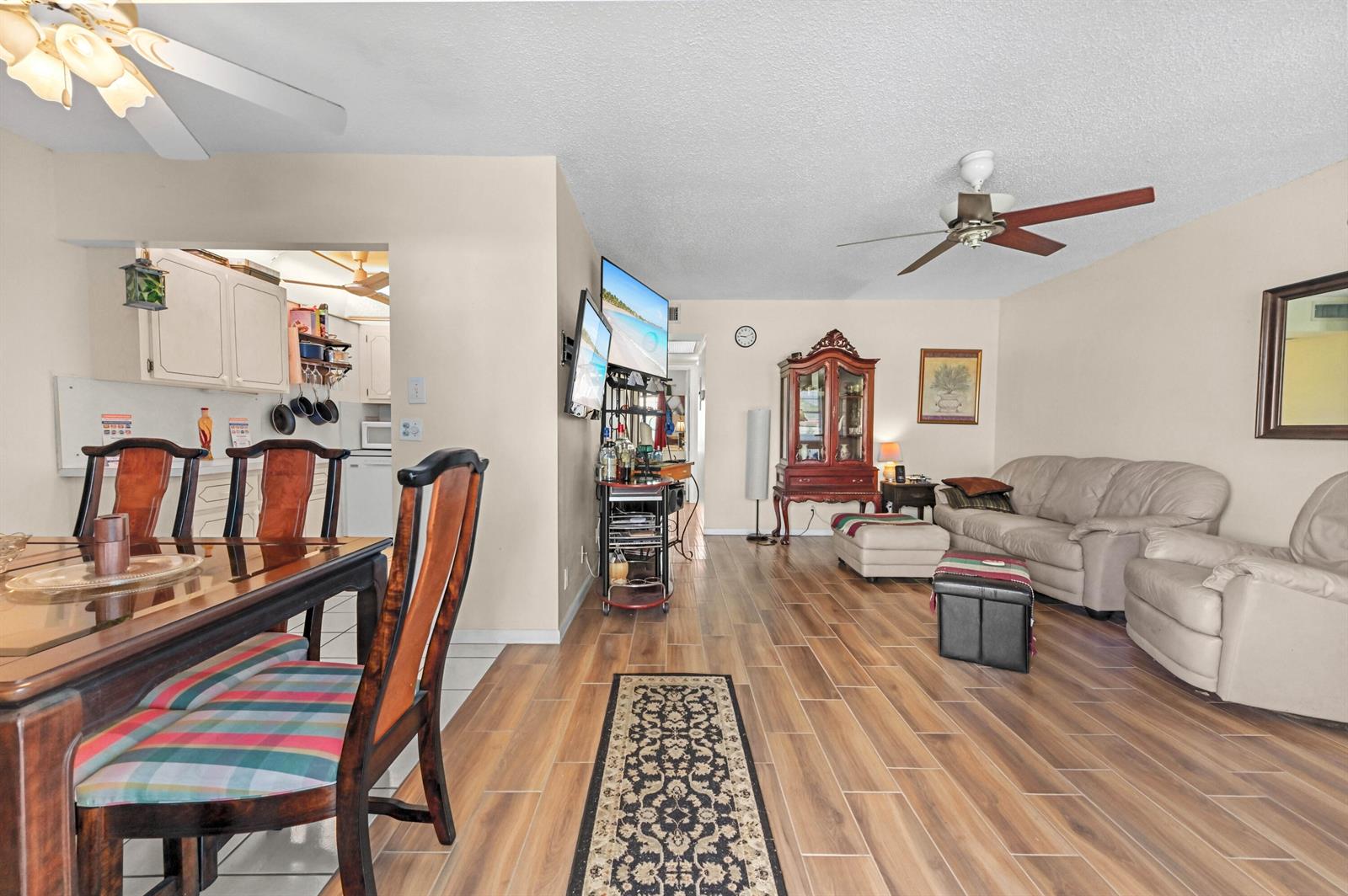 A living room and dining area feature wood-look tile flooring, a ceiling fan, and furniture — 294 Prescott O, Deerfield Beach FL 33442, DEERFIELD BEACH, FL