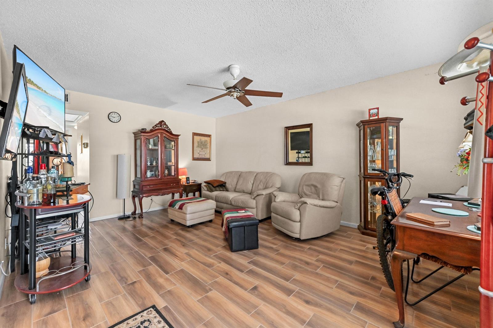 A living room features a beige sofa, a recliner, wood-look tile flooring, and a ceiling fan — 294 Prescott O, Deerfield Beach FL 33442, DEERFIELD BEACH, FL