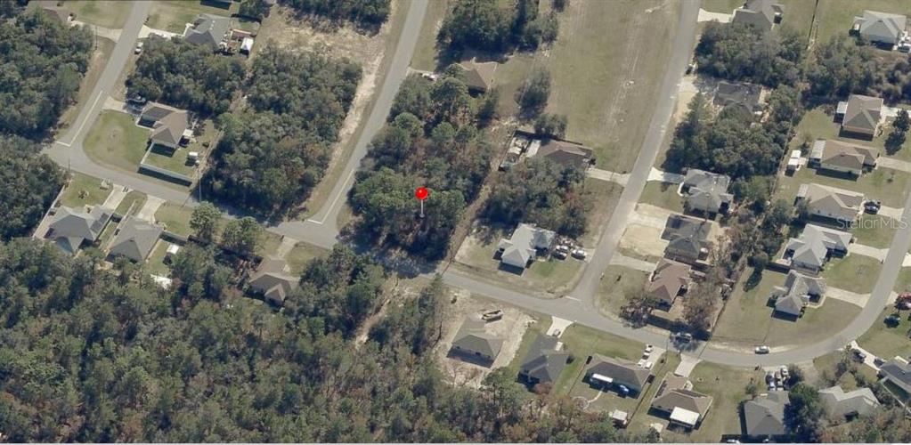 This aerial view shows a vacant, wooded residential lot marked by a red pin — SW 133 LOOP, OCALA, FL