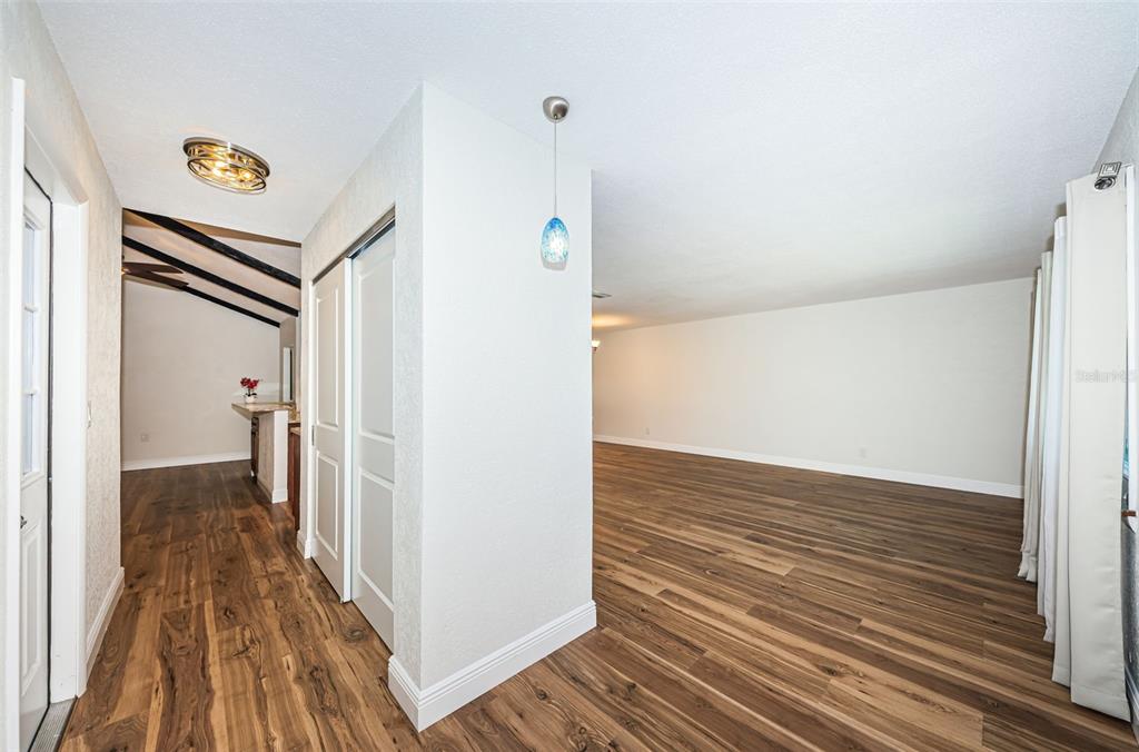 An interior view showing a hallway with wood-look flooring, a closet, and an open living area — 4723 114TH STREET N, MADEIRA BEACH, FL
