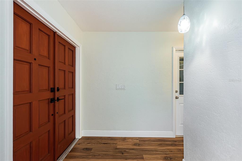 An entryway features wood-look flooring, a double front door, and a white door with glass — 4723 114TH STREET N, MADEIRA BEACH, FL