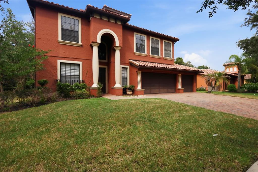 A two-story house with a terracotta exterior, arched entryway, and a three-car garage — 109 ELISSAR DRIVE, DEBARY, FL