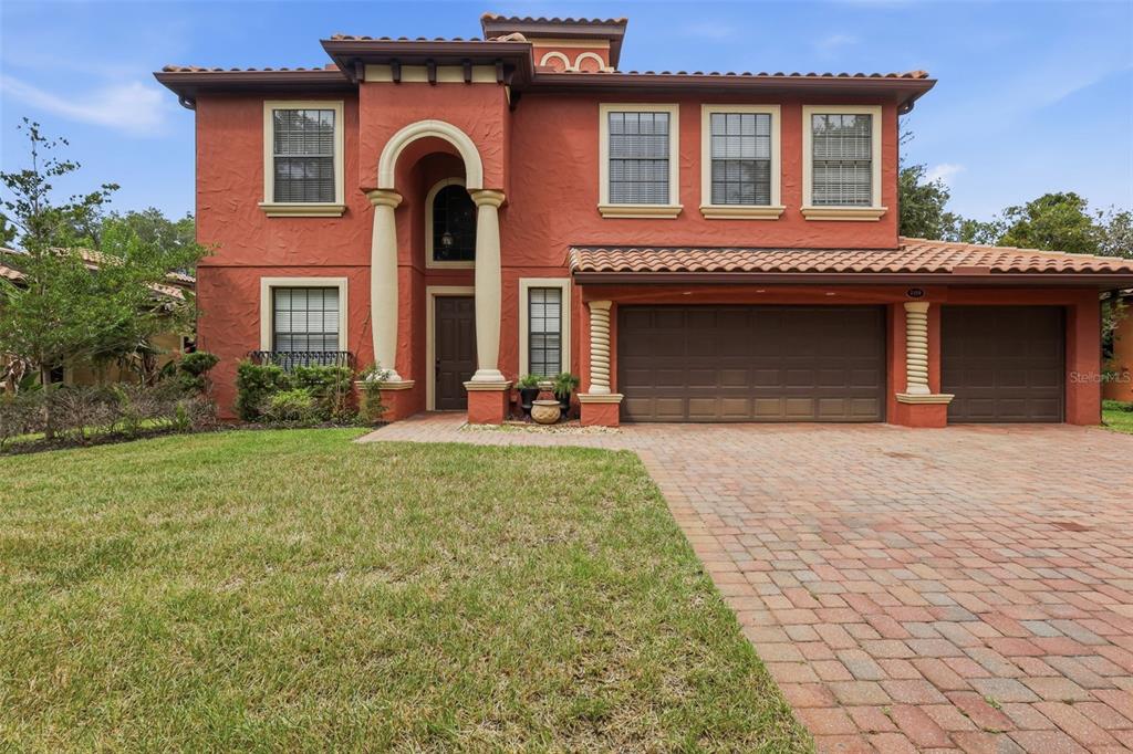 A two-story house with a red stucco exterior, arched entryway, and a three-car garage — 109 ELISSAR DRIVE, DEBARY, FL