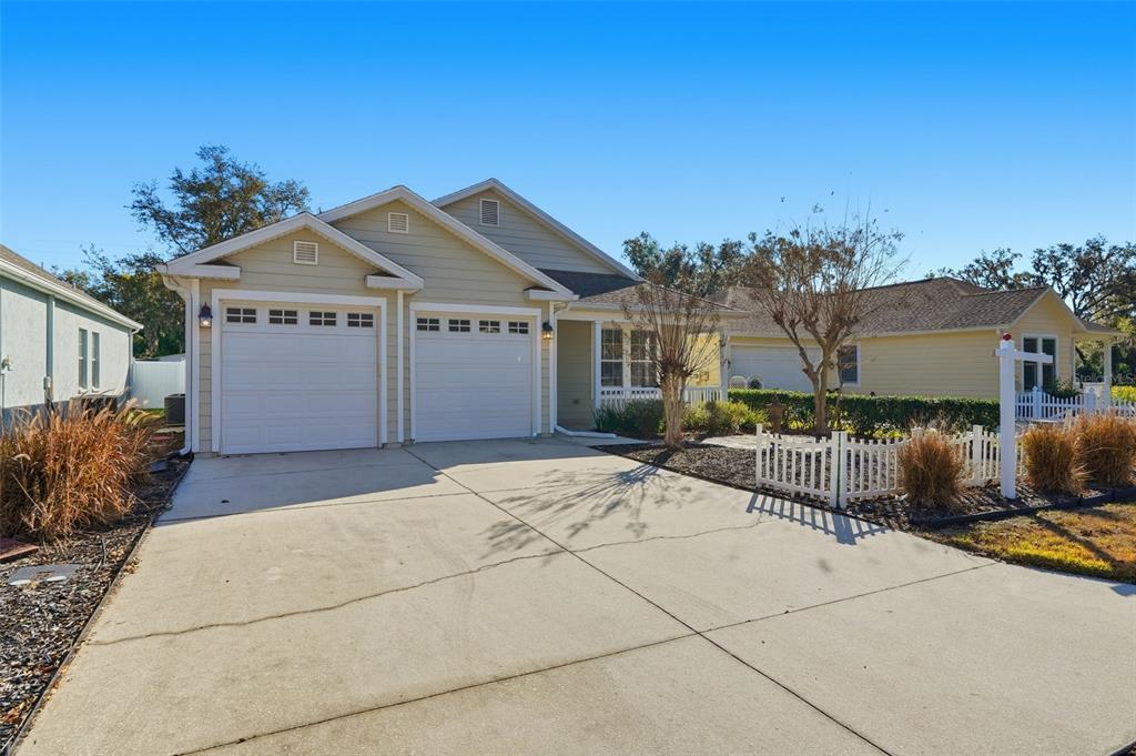 A light-colored house with a two-car garage and a small front yard with fencing — 37438 PICKETTS MILL AVENUE, ZEPHYRHILLS, FL