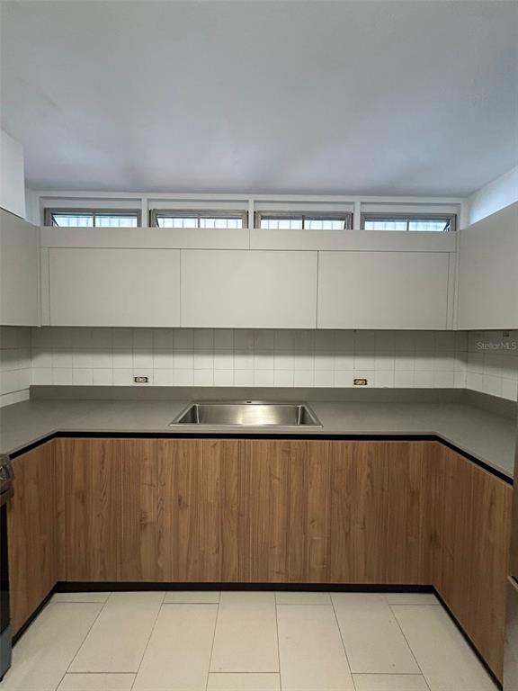 A kitchen features wood-grain lower cabinets, white upper cabinets, a gray countertop, and tiled flooring — 1309 MAGDALENA, CONDADO, PR