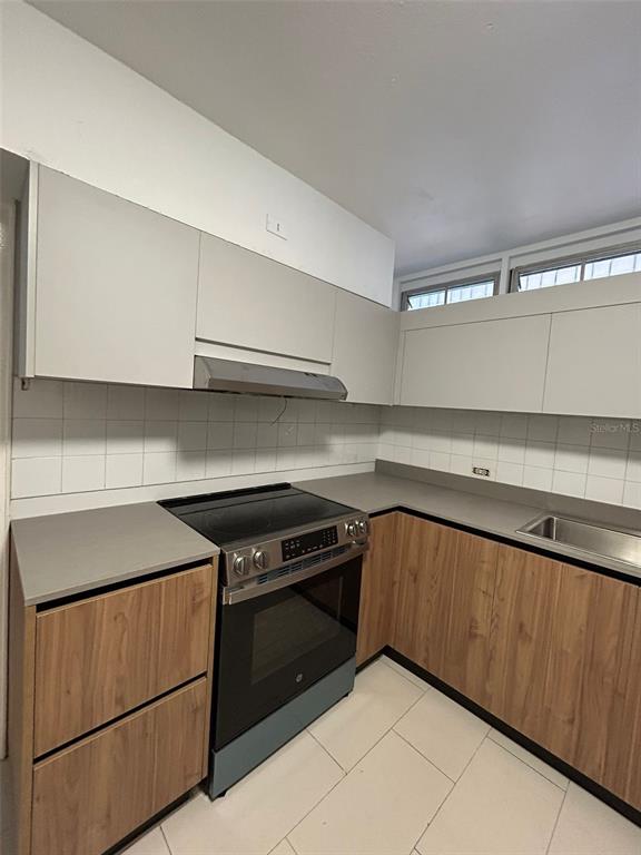 A kitchen features light wood lower cabinets, white upper cabinets, a stainless steel stove, and tile — 1309 MAGDALENA, CONDADO, PR