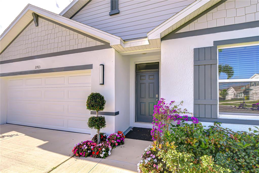 The exterior of a house features a garage, a front door, and a landscaped garden — 2763 WIDEWATER WAY, ZEPHYRHILLS, FL