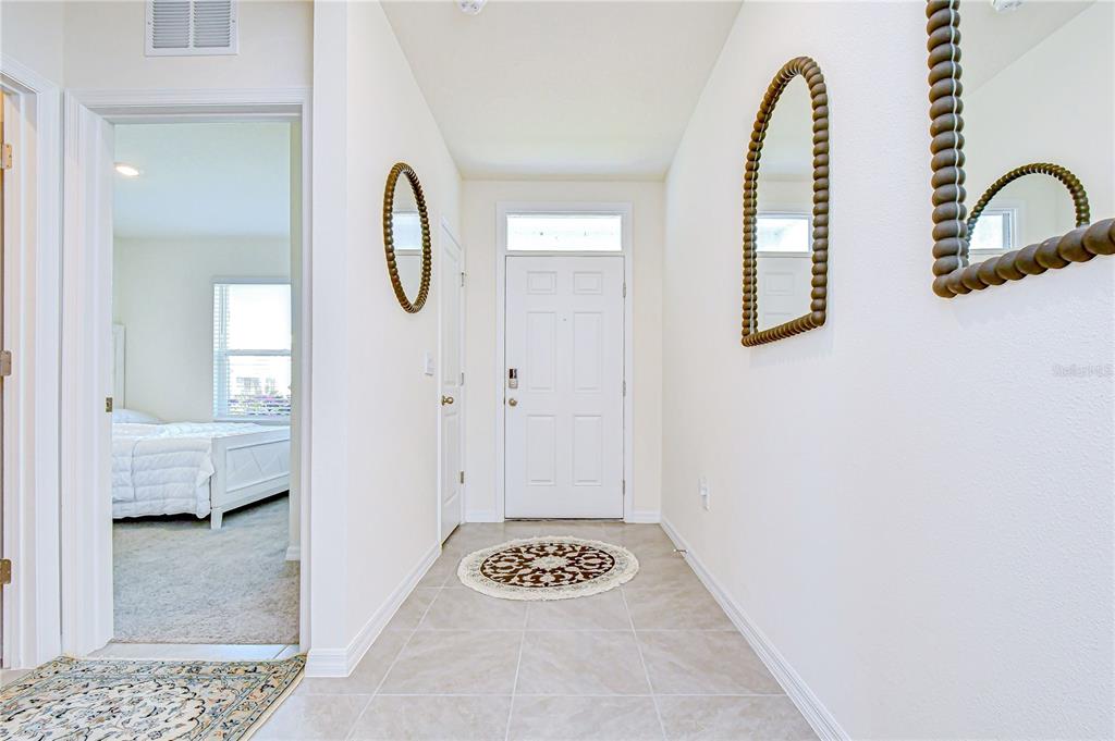 A tiled entryway features a white front door, two mirrors, and a bedroom doorway — 2763 WIDEWATER WAY, ZEPHYRHILLS, FL