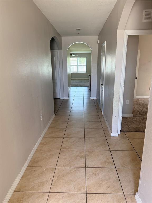 A tiled hallway leads through an arched doorway toward a room with a window — 615 TRALEE LANE, AUBURNDALE, FL