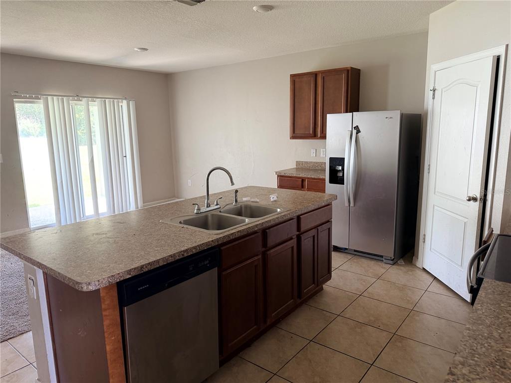 A kitchen features a central island with a sink, stainless steel appliances, and dark wood cabinetry — 615 TRALEE LANE, AUBURNDALE, FL
